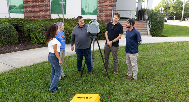 Professor showing students geomatics equipment